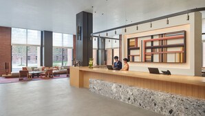A modern reception area with a reception desk, seating area, and a bookshelf. - Hyatt Place Jingdezhen Taoxichuan (Jingdezhen)