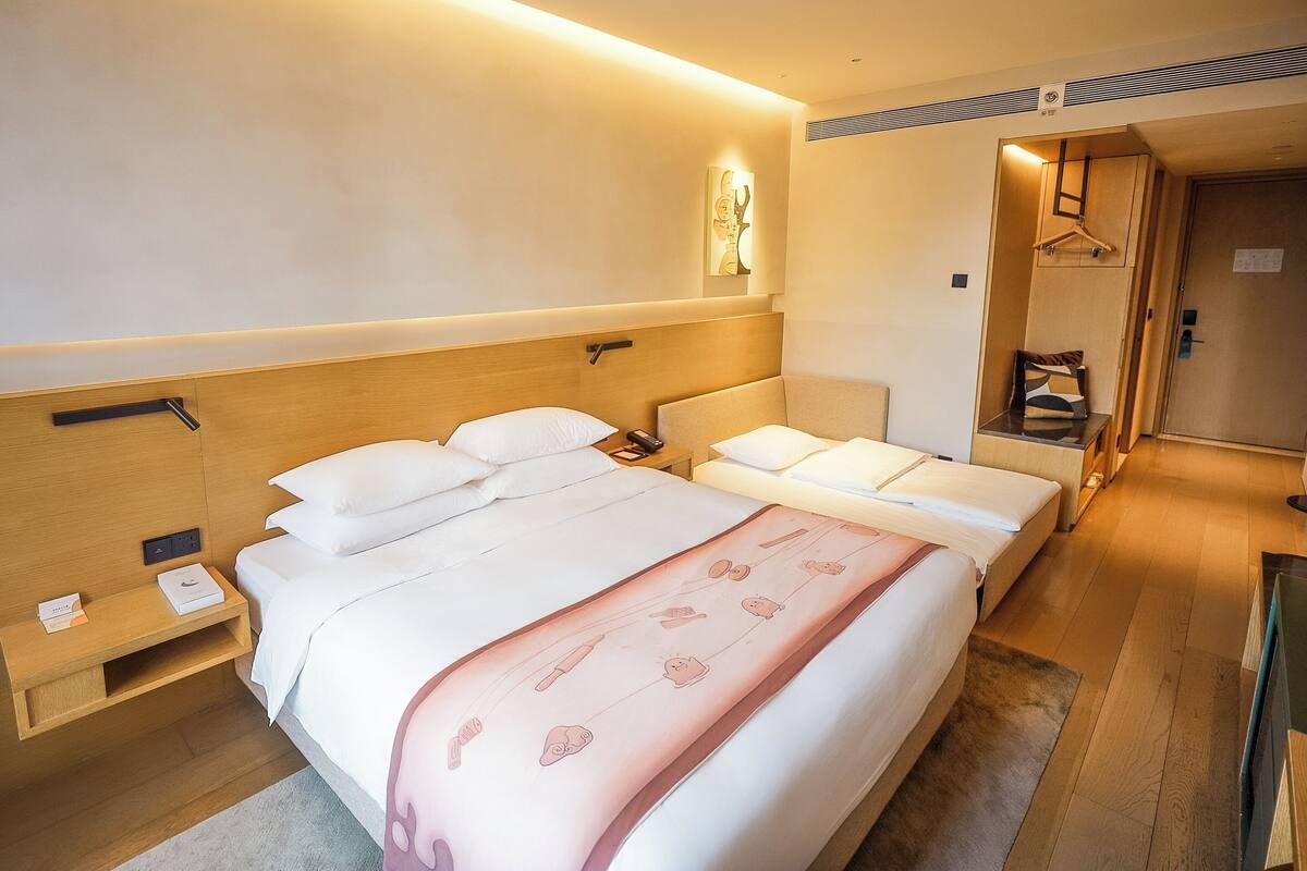 Ett hotellrum med en stor säng, sängbord, en klädställning och en liten sittgrupp.