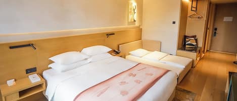 Habitación de hotel con una cama grande, mesitas de noche, perchero y una pequeña zona de estar.