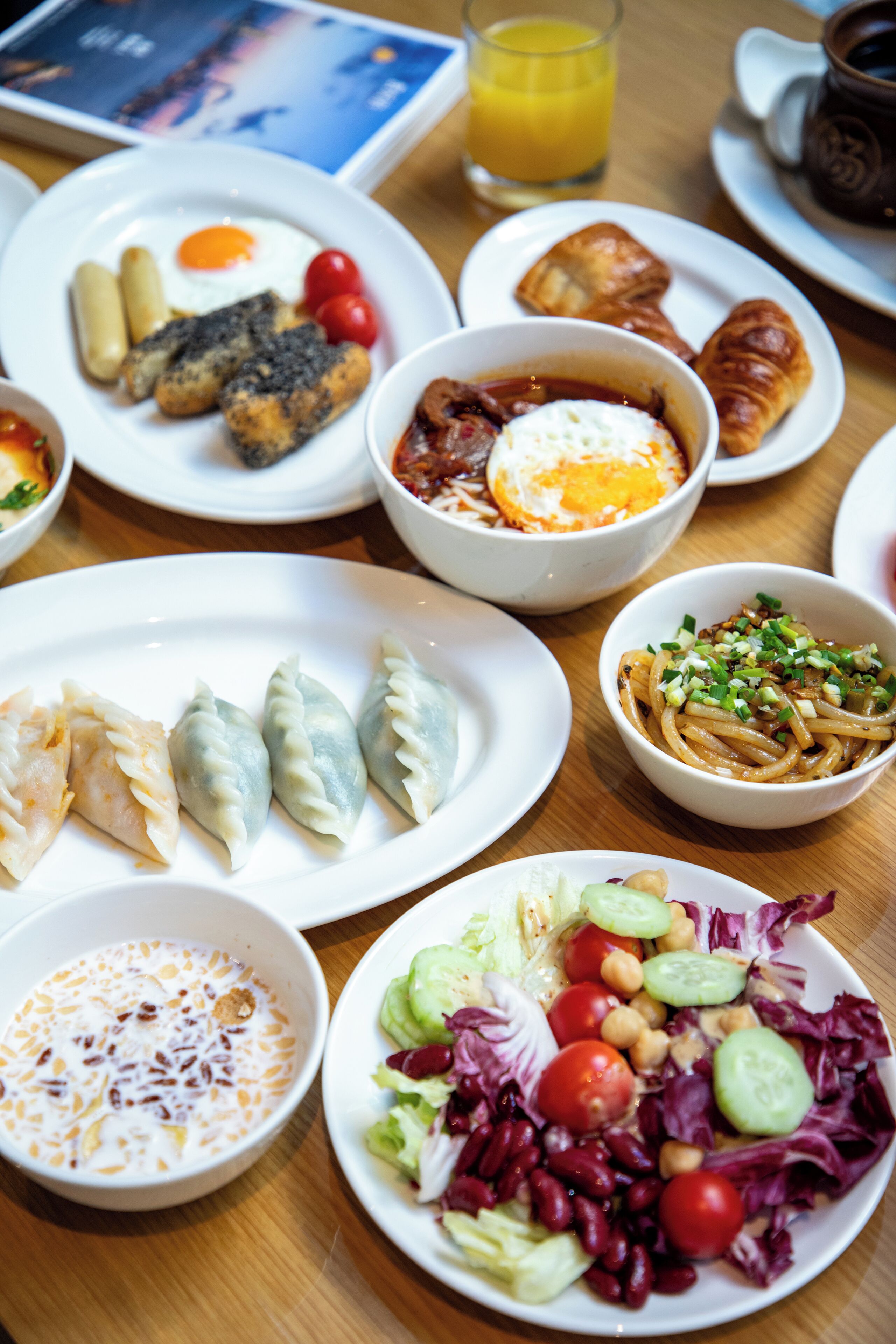 A variety of dishes on a table, including eggs, sausages, and salads.
