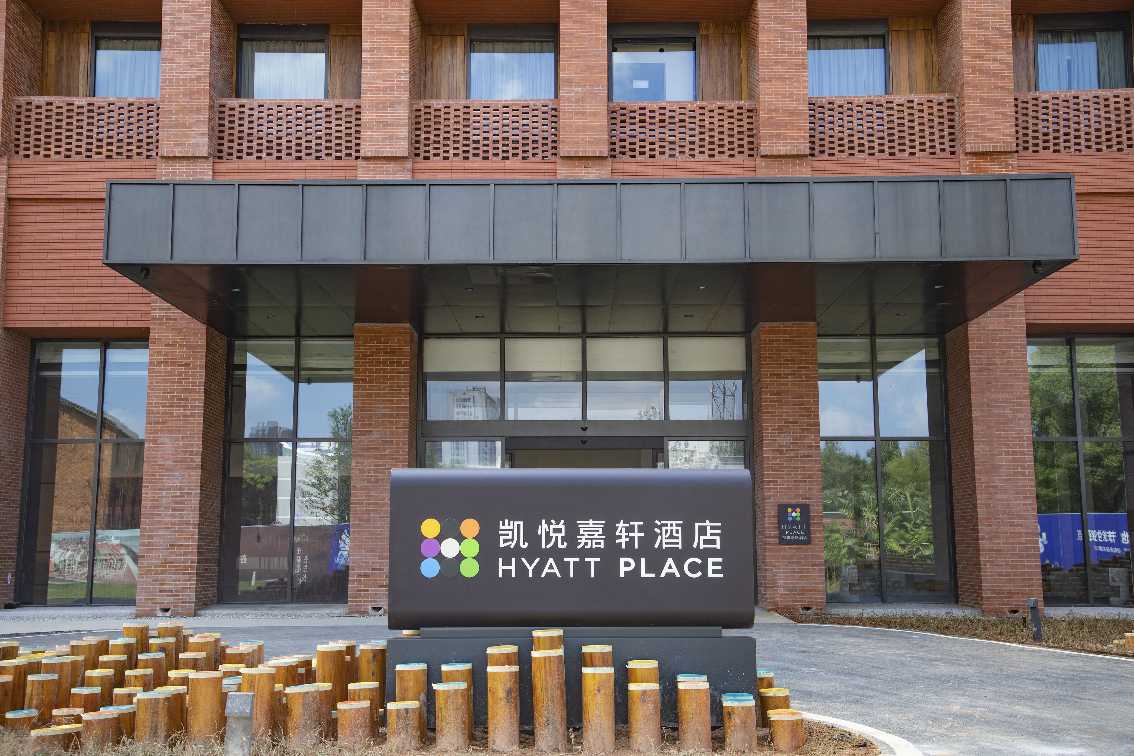 A Hyatt Place hotel entrance with a modern brick facade, large glass windows, and a signboard.