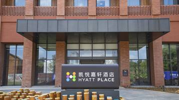 A Hyatt Place hotel entrance with a modern brick facade, large glass windows, and a signboard.