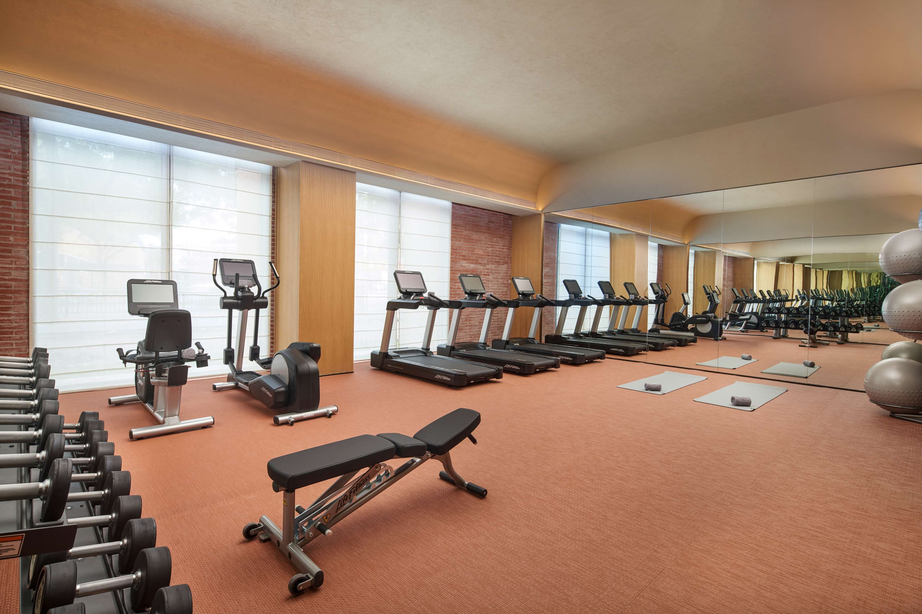Un gimnasio con cintas de correr, mancuernas y colchonetas de ejercicio.
