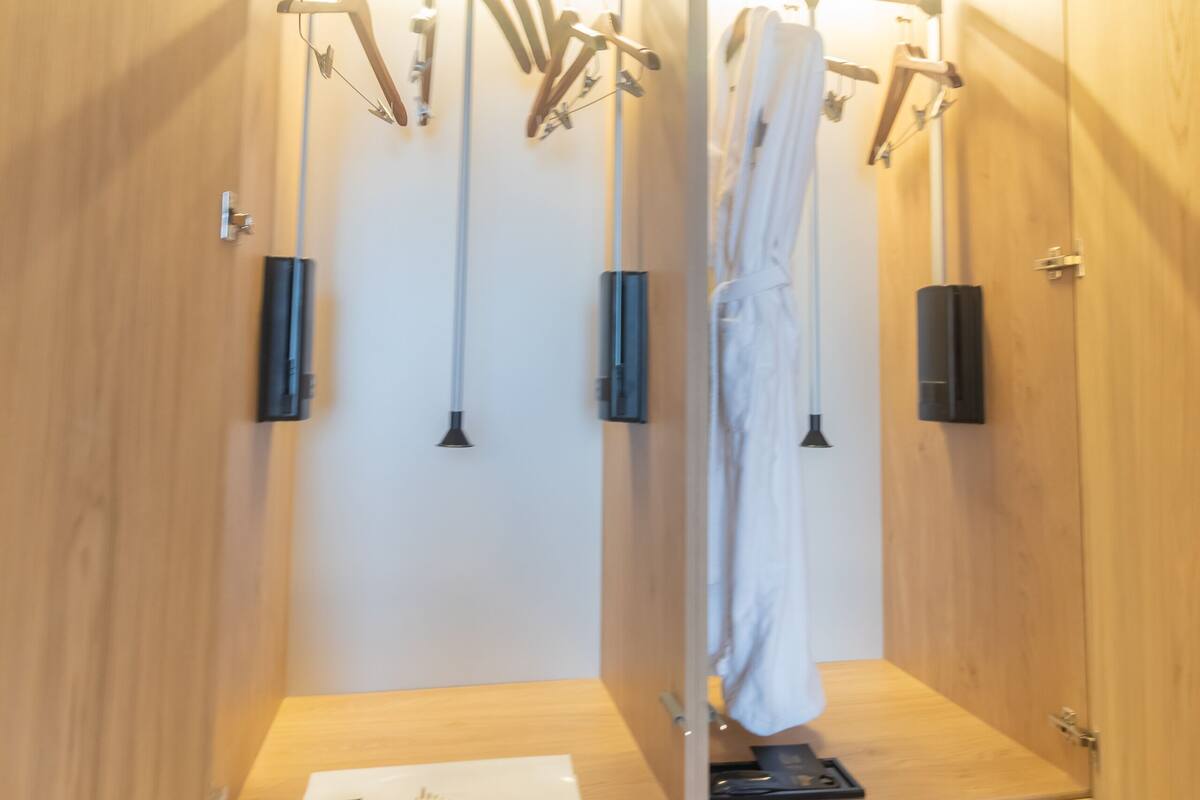 A wooden cabinet with a mirror, a robe, and a towel hanging on hooks.