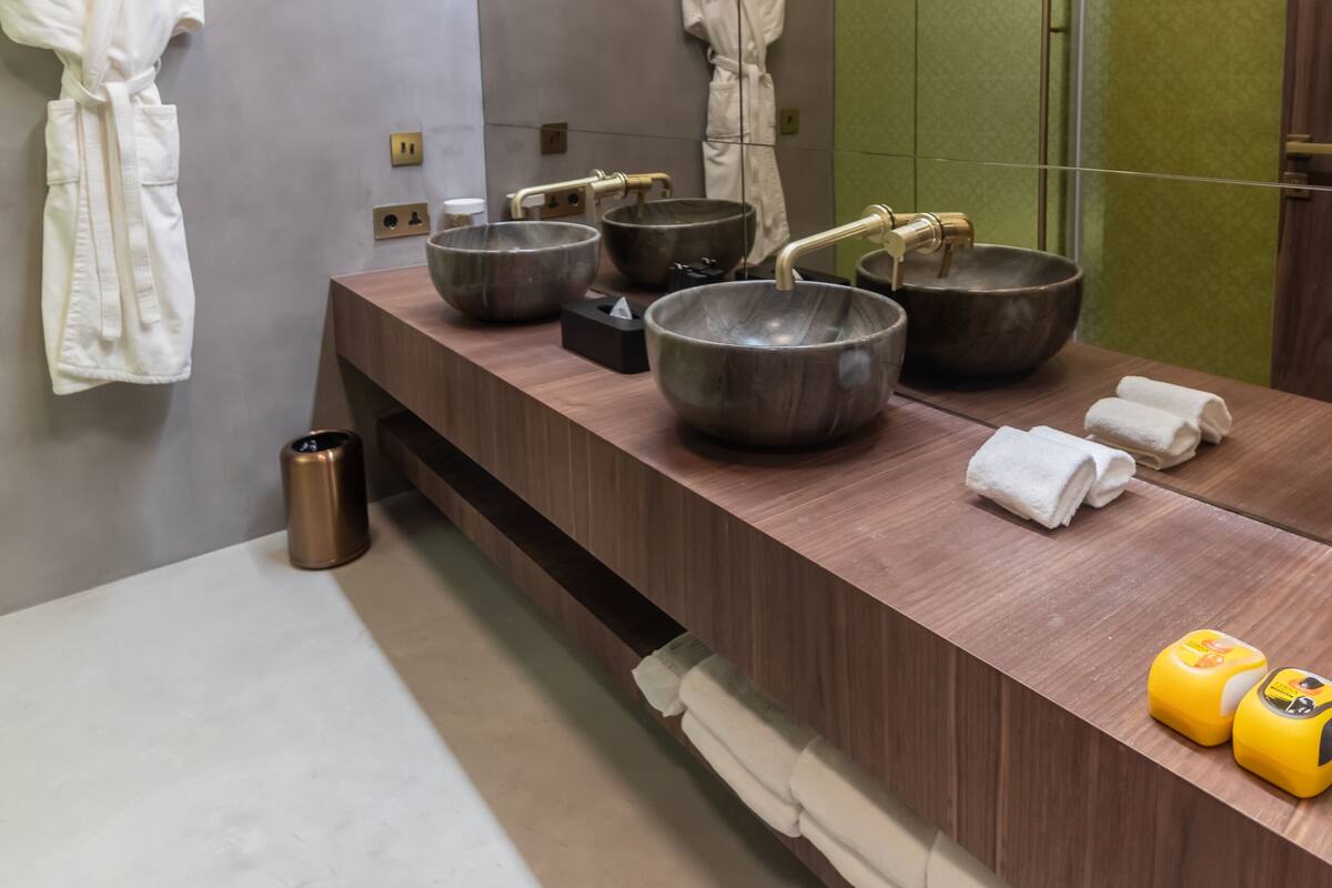 A modern bathroom with a wooden vanity, large bowls, and a mirror.