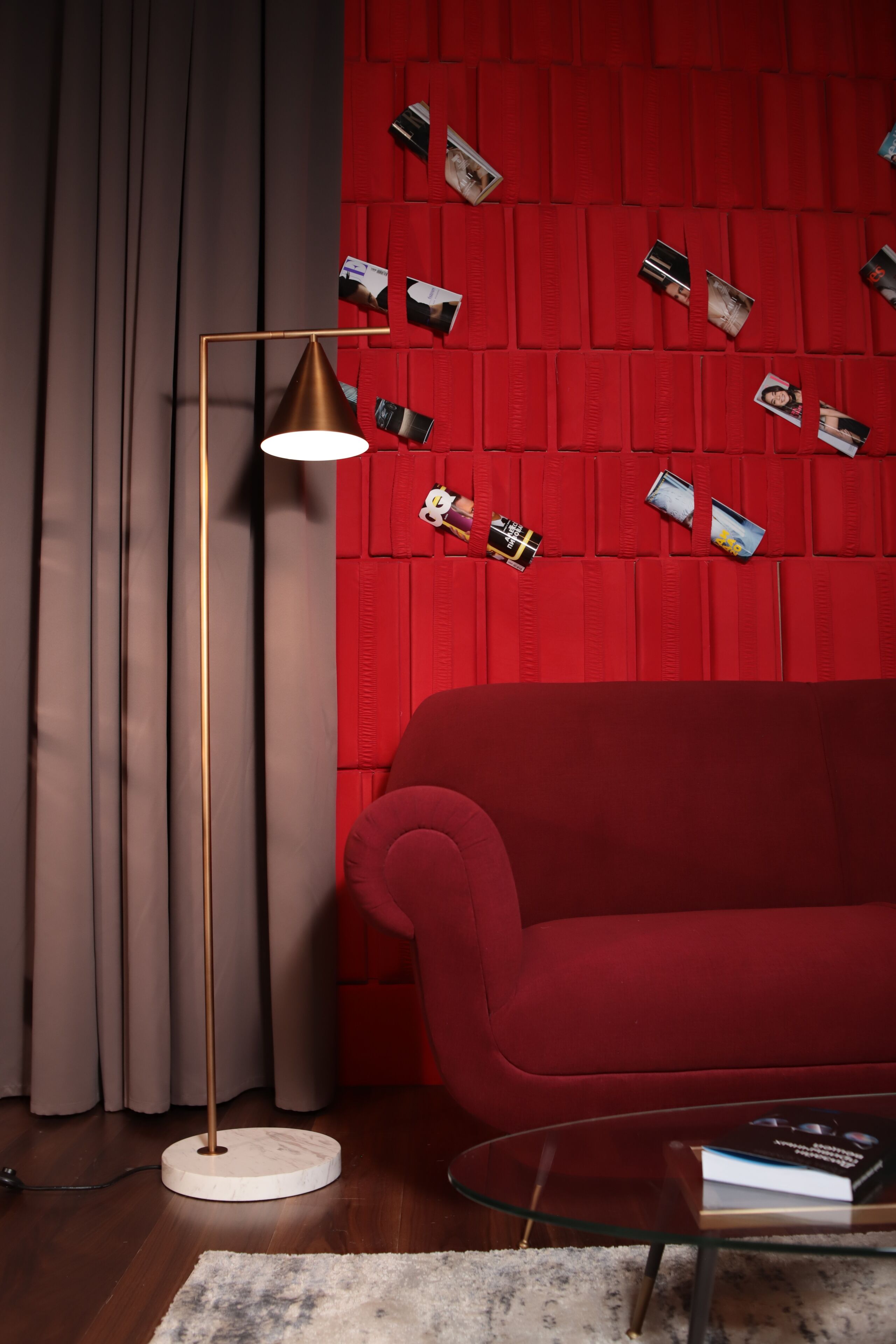 Una sala de estar moderna con un sofá rojo, una lámpara de pie y una mesa de centro de vidrio.