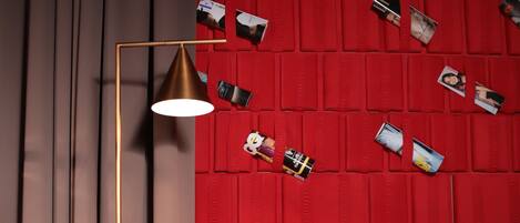 A modern living room with a red sofa, a floor lamp, and a glass coffee table.