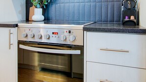 A kitchen with a stainless steel stove, oven, and a microwave above it. There is a potted plant on the counter and a coffee maker. - Bright Loft · Queen Bed | Walk Everywhere (Québec City)