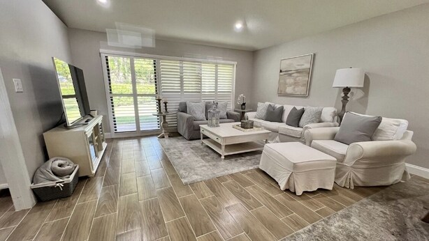 A living room with a sofa set, a coffee table, a TV, and a lamp. - Beautiful Cottage located inside PGA National (Palm Beach Gardens)