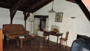 Una sala de estar acogedora con un sofá de cuero marrón, una mesa de centro de madera, una mesa de comedor con sillas, un televisor y una chimenea.