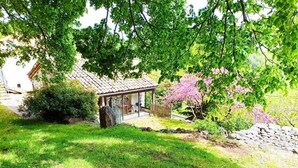 Una casa rústica con un muro de piedra y una terraza de madera.