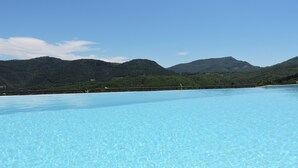 Una piscina azul cristalina con vistas a montañas verdes al fondo.