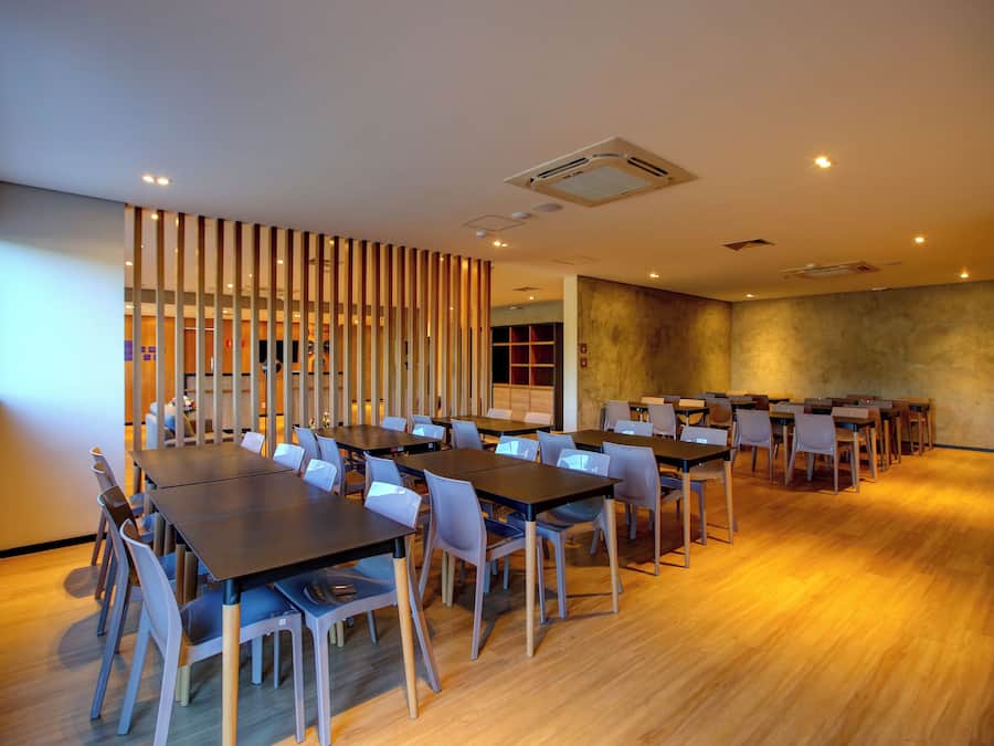 Un salón de conferencias con varias mesas y sillas, un separador de madera y un ventanal grande.