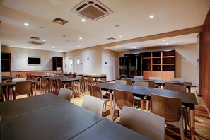 A conference room with multiple tables and chairs, a flat-screen TV, and a large window. - Transamerica Fit Lucas Do Rio Verde (Lucas do Rio Verde)