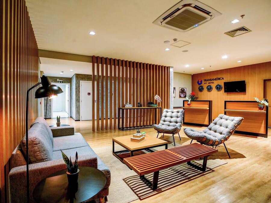 Un moderno vestíbulo de hotel con un sofá, sillones, una mesa de centro y una recepción.