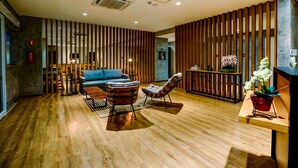 A modern interior with wooden flooring, a blue sofa, striped armchairs, and a wooden partition. - Transamerica Fit Lucas Do Rio Verde (Lucas do Rio Verde)