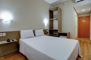 A hotel room with a bed, bedside tables, a desk, a wardrobe, and a door. - Transamerica Fit Lucas Do Rio Verde (Lucas do Rio Verde)