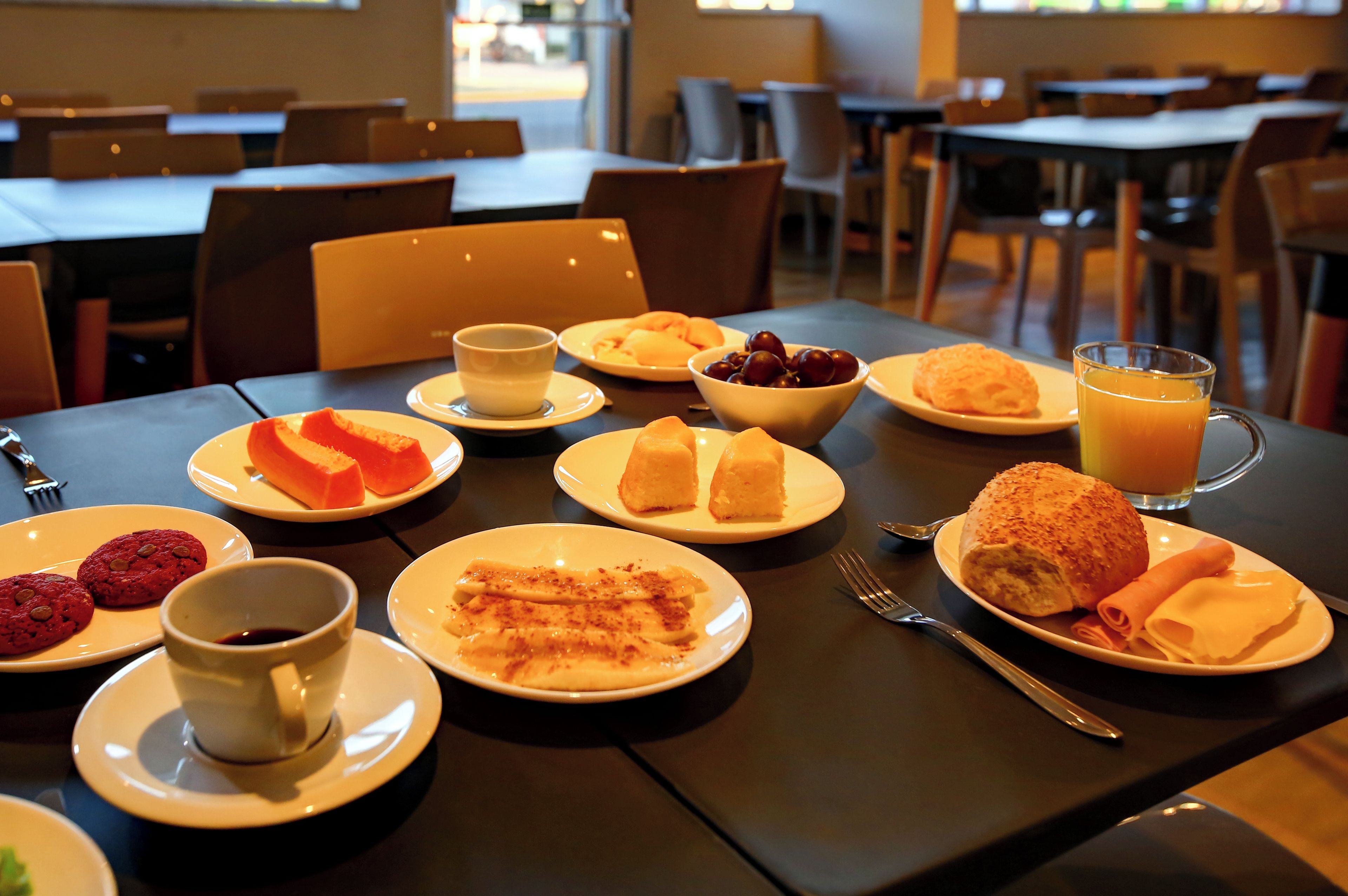 Ett matbord dukat med olika frukosträtter, inklusive bakverk, ett glas apelsinjuice och en kopp kaffe.