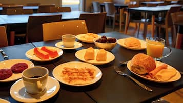 Ett matbord dukat med olika frukosträtter, inklusive bakverk, ett glas apelsinjuice och en kopp kaffe.