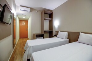 Habitación de hotel con dos camas, televisión, armario y escritorio.