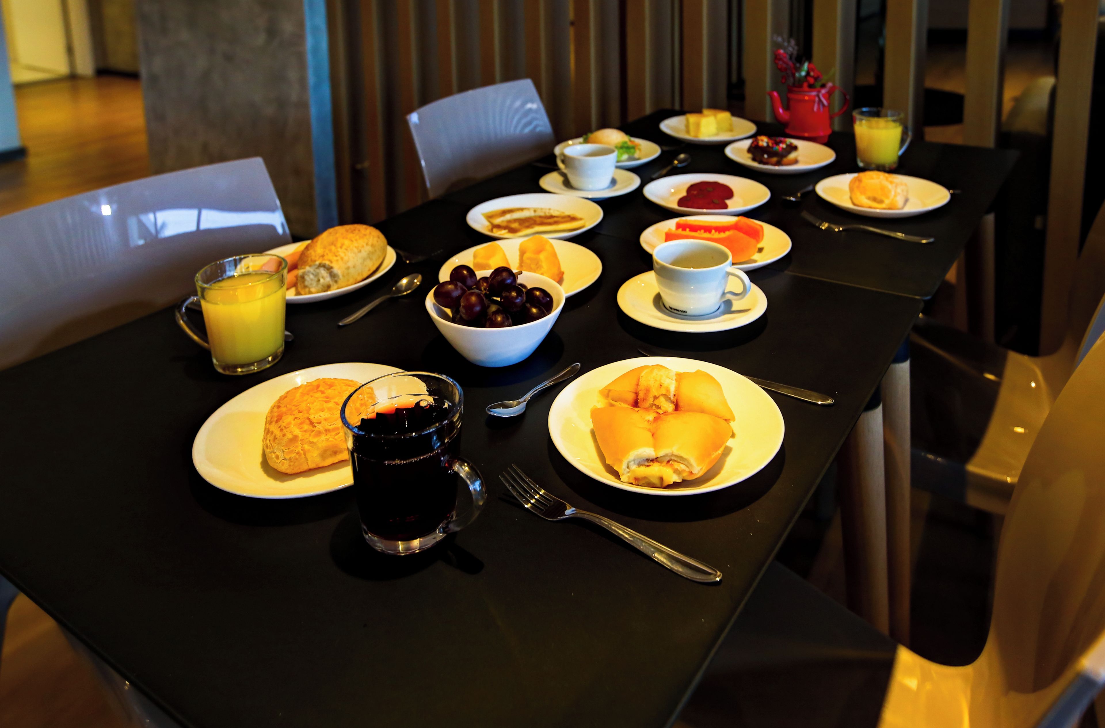Ein Frühstückstisch reichhaltig gedeckt mit Speisen, darunter Eier, Toast und Obst, sowie Getränke und Besteck.