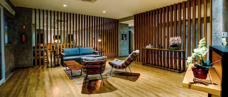 A modern interior with wooden flooring, a blue sofa, striped armchairs, and a wooden partition.