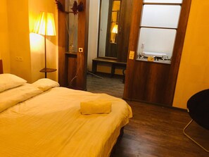 A hotel room with a bed, a bedside table, a lamp, a mirror, and a bathroom visible through an open door. - Apartment near Dry Bridge (Tbilisi)