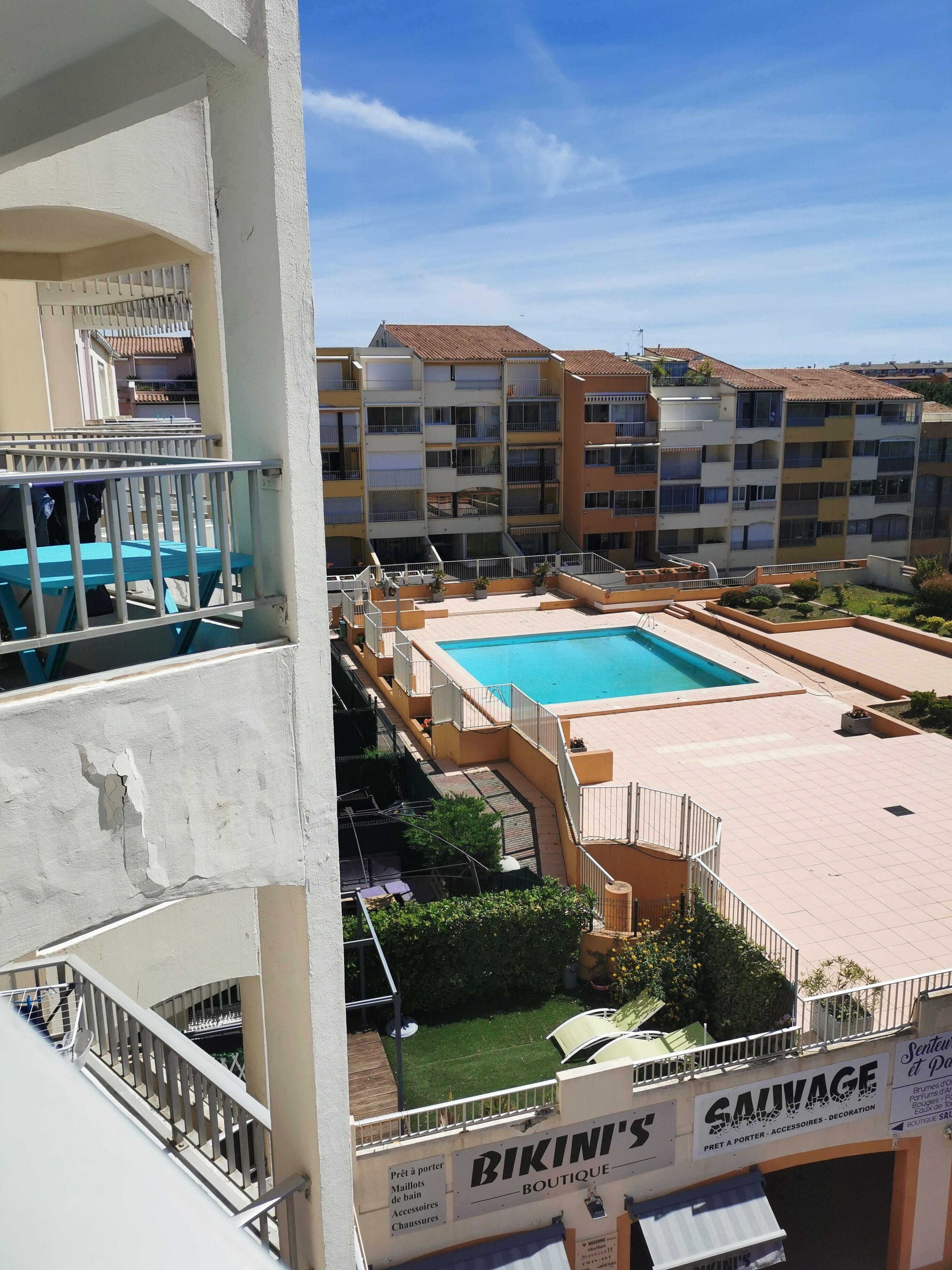 Un espace piscine aménagé sur le toit, avec une enseigne indiquant « Bikini's Boutique » et « Savage ».