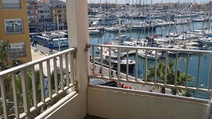 Een balkon met uitzicht op een jachthaven vol boten, een gebouw met balkons en een heldere lucht.