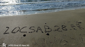 Een strand met voetafdrukken en de tekst 'LOCSAB 28.19' in het zand geschreven.