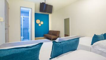 A hotel room with two beds, a TV, a sofa, and a bathroom visible through an open door.