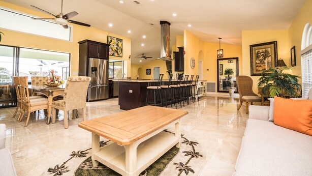 A spacious living area with a large wooden table, a sofa, and a dining area with chairs. - Palm Tree III Pool Home Waterfront  (Apollo Beach)