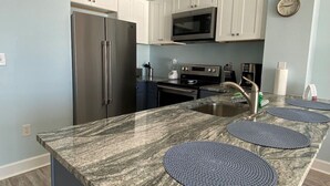 A modern kitchen with granite countertops, stainless steel appliances, and white cabinetry.