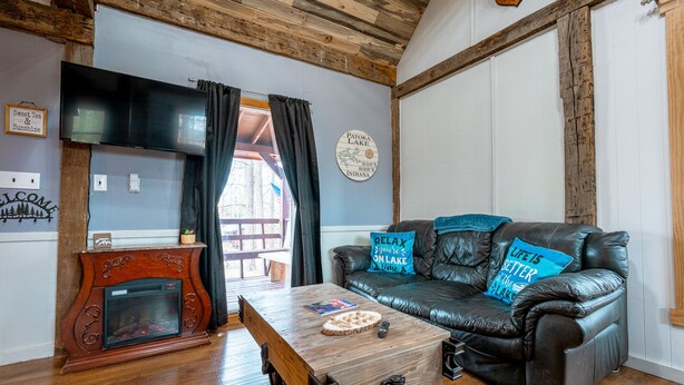 Een gezellige woonkamer met een open haard, een leren bank met decoratieve kussens, en een houten salontafel.