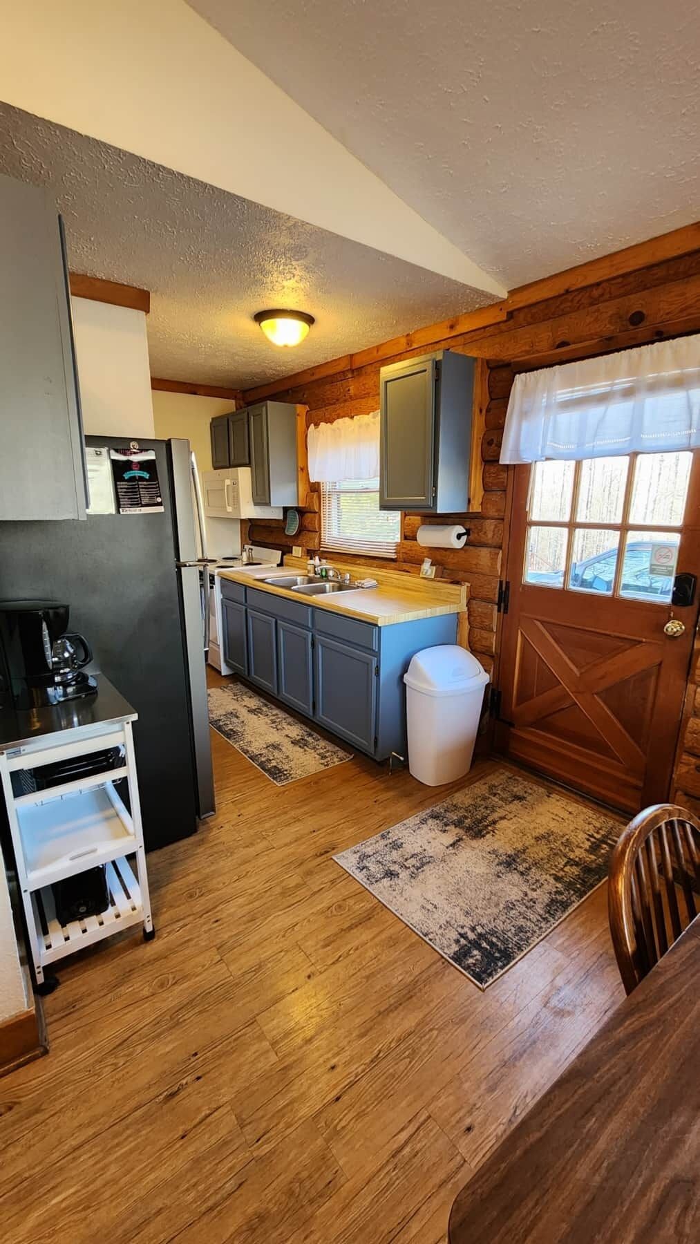 A compact kitchen with wooden cabinets, a sink, and a refrigerator.