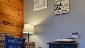 Una sala de estar acogedora con un sofá de cuadros, una almohada azul, una lámpara, una chimenea y dos adornos de pared.