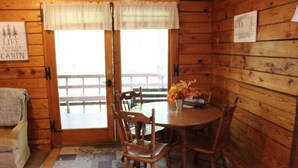 L’intérieur d’une cabane avec une table et des chaises en bois, un banc à l’extérieur et un panneau sur le mur.