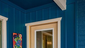 Una porta blu con un pannello di vetro, un tappetino colorato all'ingresso e un quadro vivace appeso al muro.