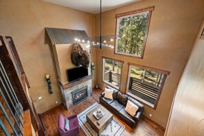 A cozy living room with a fireplace, a sofa, and a coffee table. - Gray Goose Lodge - Private back deck, hot tub and (Lead)