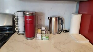 Una encimera de cocina con una cafetera, un hervidor y una caja de Truvia.