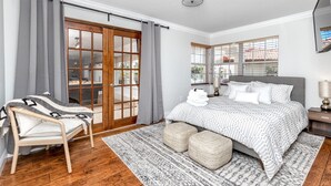 Un dormitorio con cama, una silla, una ventana y una puerta.