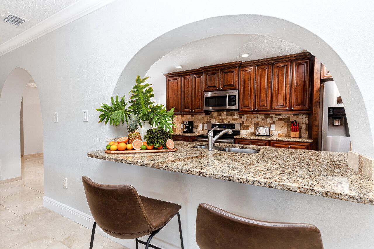 A kitchen with granite countertops, wooden cabinets, a stainless steel microwave, and a sink.