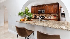 A kitchen with granite countertops, wooden cabinets, a stainless steel microwave, and a sink.