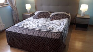 Un lit recouvert d’une couvre-lit à motifs, deux tables de chevet avec des lampes et une fenêtre avec des rideaux.