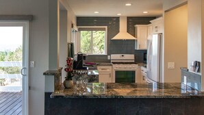 Una cocina moderna con encimeras de granito, armarios blancos y una isla grande con taburetes de bar.