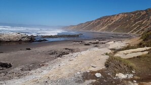 Una playa costera con terreno rocoso y una vista despejada del océano.