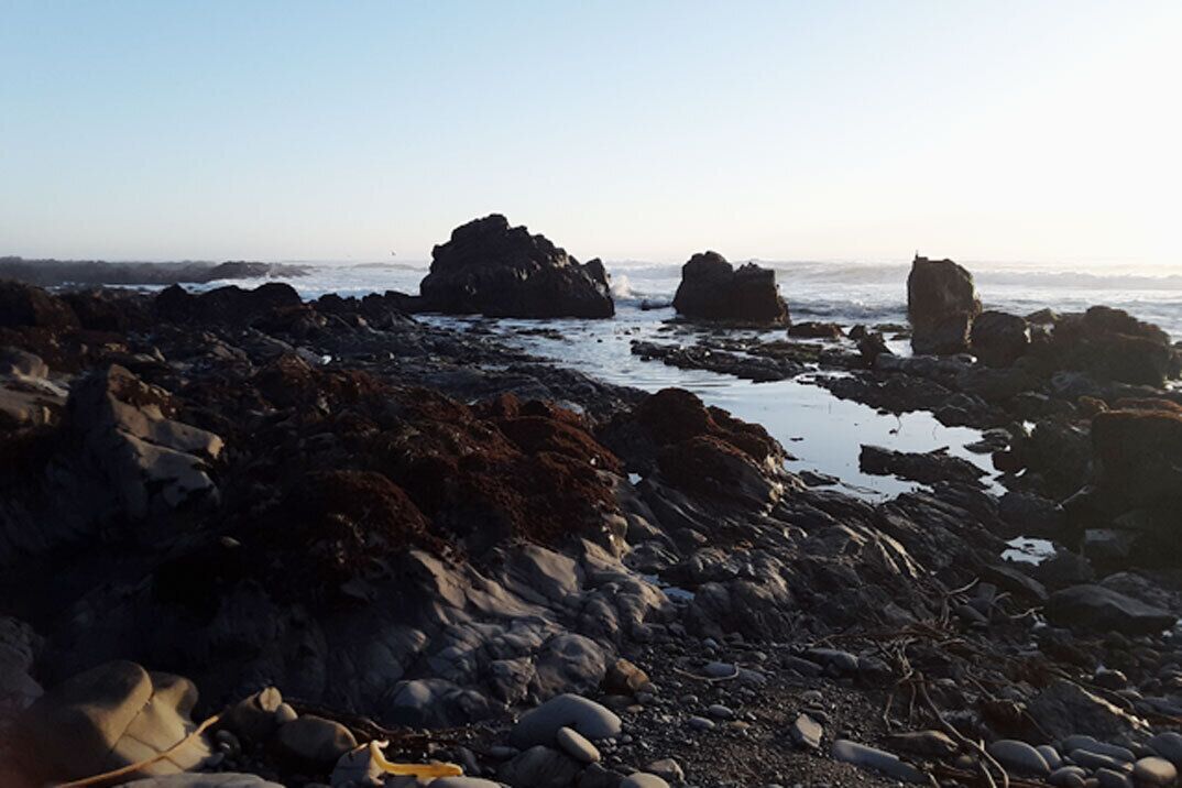 A rocky shoreline with large boulders and a calm sea.