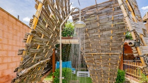 A rustic outdoor area with a bamboo structure, a metal water spout, and a small seating area. - Cubo's Villa Lula (Cártama)
