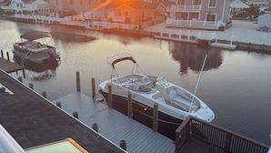 A marina with boats docked, a sunset in the background, and residential buildings nearby.