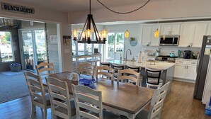 A spacious kitchen with white cabinetry, a central island, and a dining area with wooden chairs and a table.